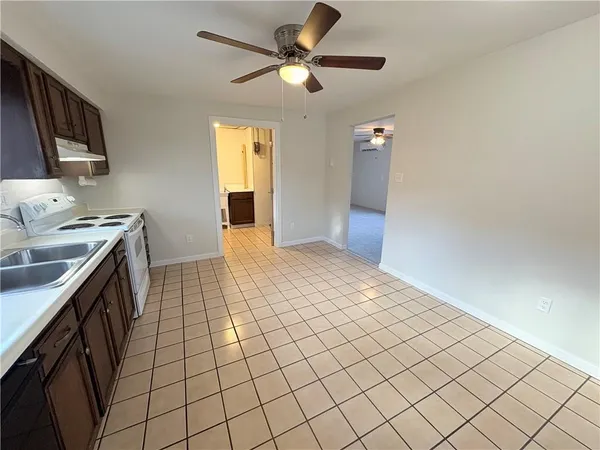 a kitchen with a sink a stove top oven cabinets and a window