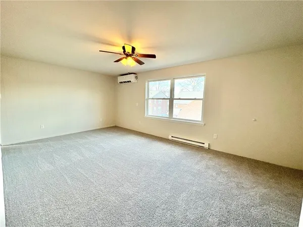 an empty room with windows and chandelier fan