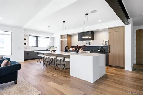a living room with stainless steel appliances kitchen island granite countertop a table chairs and a refrigerator