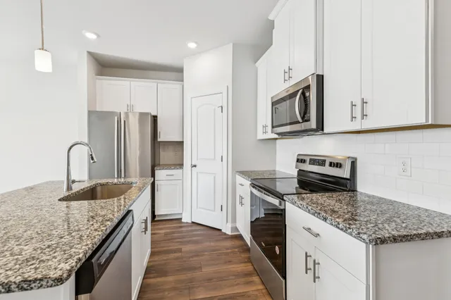 a kitchen with stainless steel appliances granite countertop a sink stove microwave and refrigerator