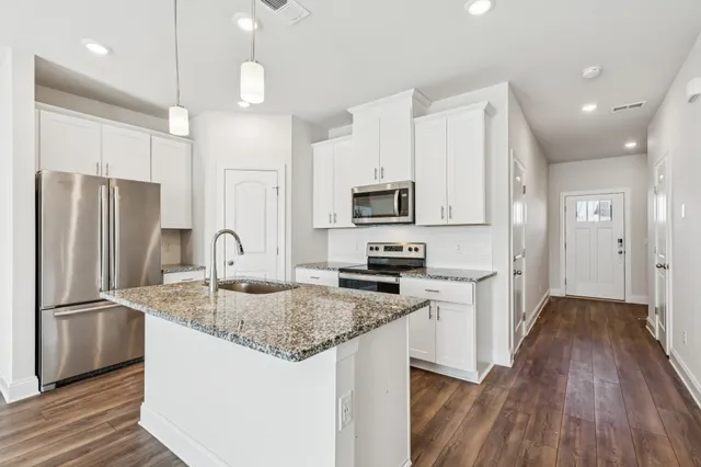 a kitchen with stainless steel appliances granite countertop a refrigerator a stove a sink cabinets and wooden floor