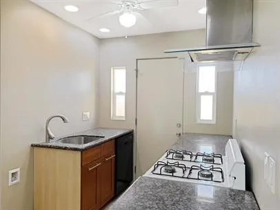 a kitchen with kitchen island granite countertop a sink cabinets a stove and a window