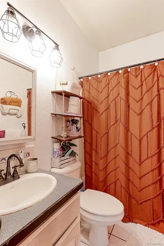 a bathroom with a sink a toilet and shower curtain