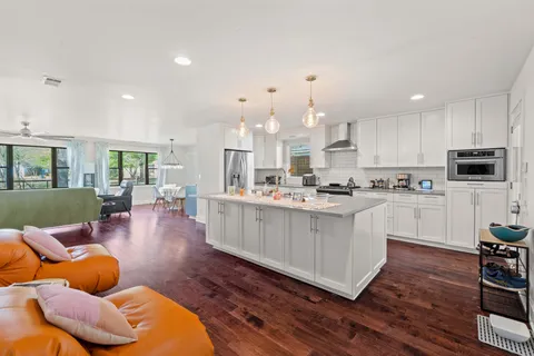 a kitchen with stainless steel appliances granite countertop a refrigerator a stove top oven a sink dishwasher and white cabinets with wooden floor