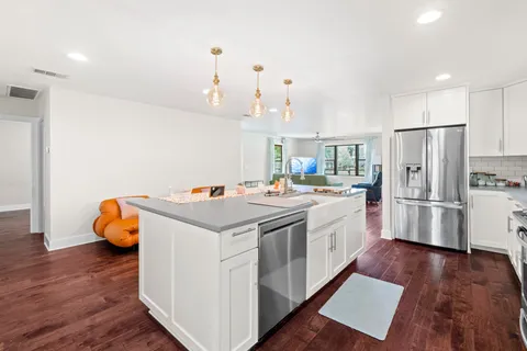 a kitchen that has a lot of white cabinets and stainless steel appliances