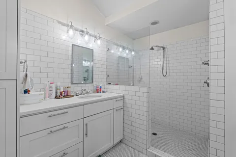 a bathroom with a double vanity sink mirror and shower
