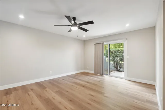 an empty room with wooden floor fan and windows