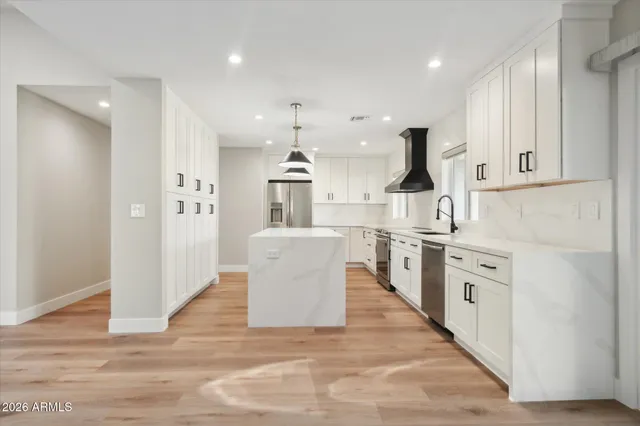a large kitchen with white cabinets and stainless steel appliances
