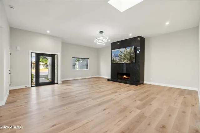 a view of an empty room with window and wooden floor