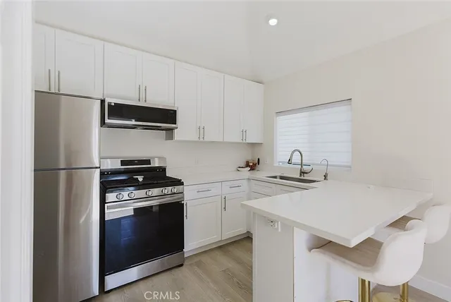 a kitchen with stainless steel appliances a sink a stove a refrigerator and cabinets