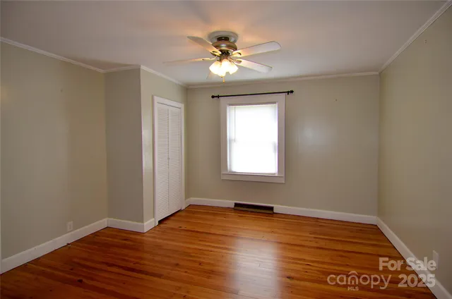 a view of a room with wooden floor and a ceiling fan