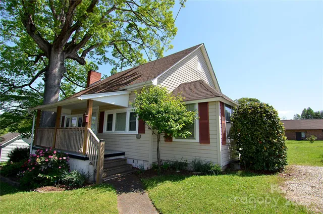 a view of a house with a yard plants and large tree