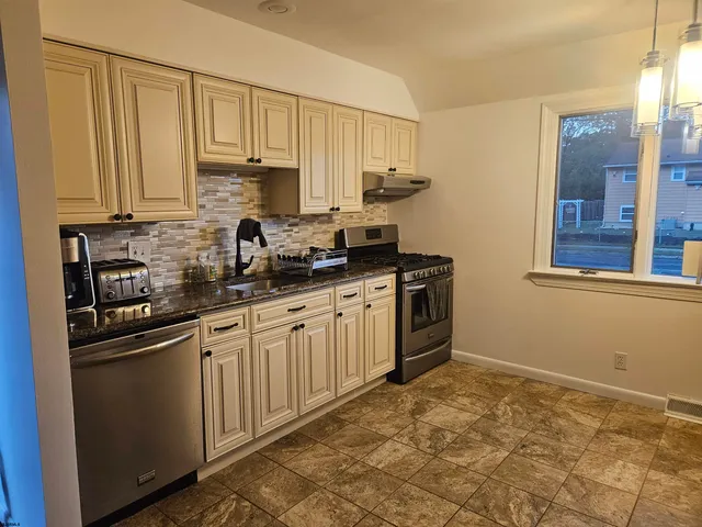 a kitchen with stainless steel appliances granite countertop a stove a sink and white cabinets