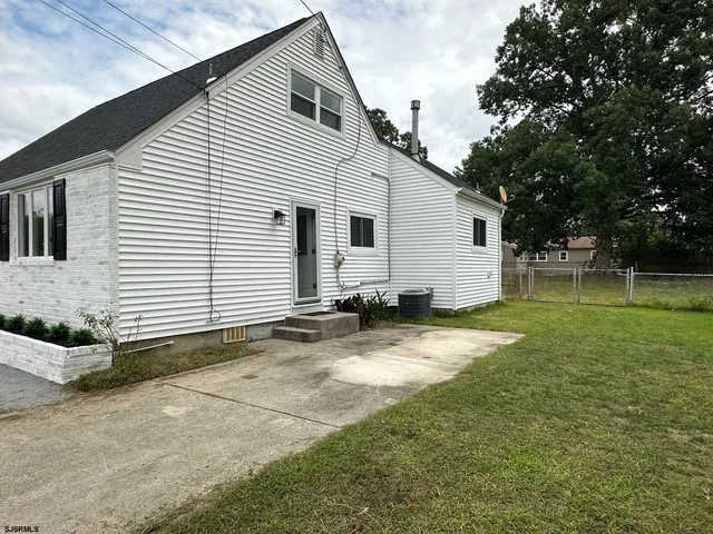 a view of a white house with a yard and sitting area