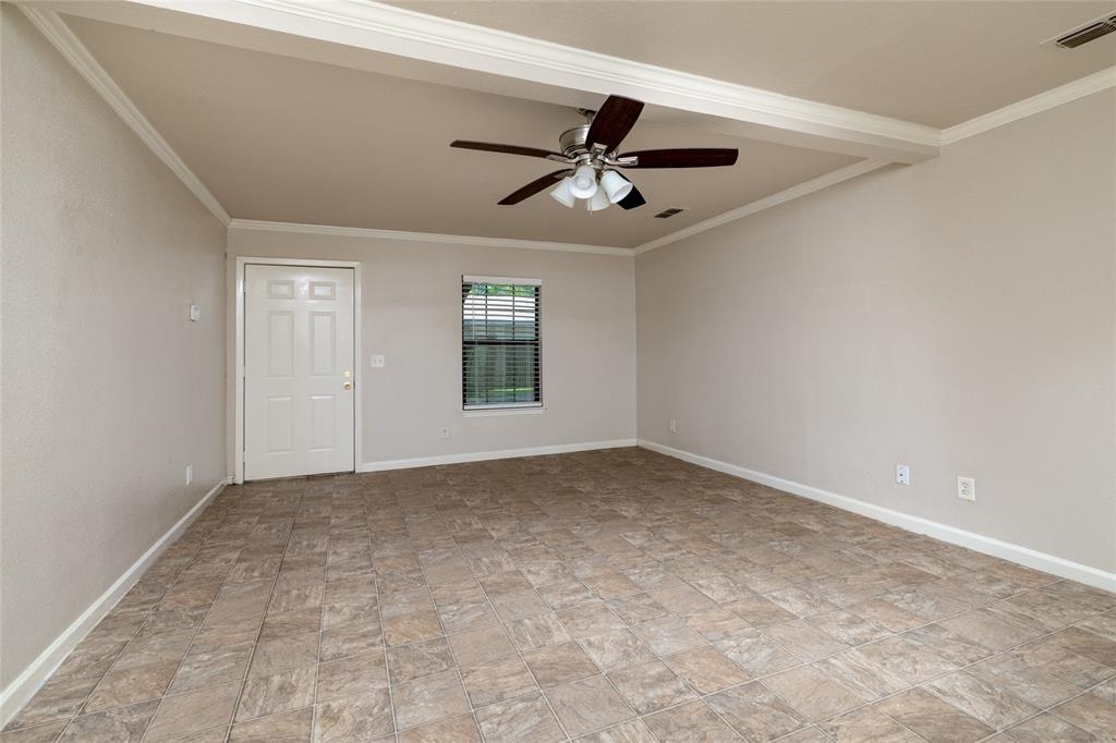313 North Roe Street White Settlement, TX 76108 - Photo 6 of 33 Spacious room featuring tile flooring, a ceiling fan, crown molding, a window with blinds, and a paneled door