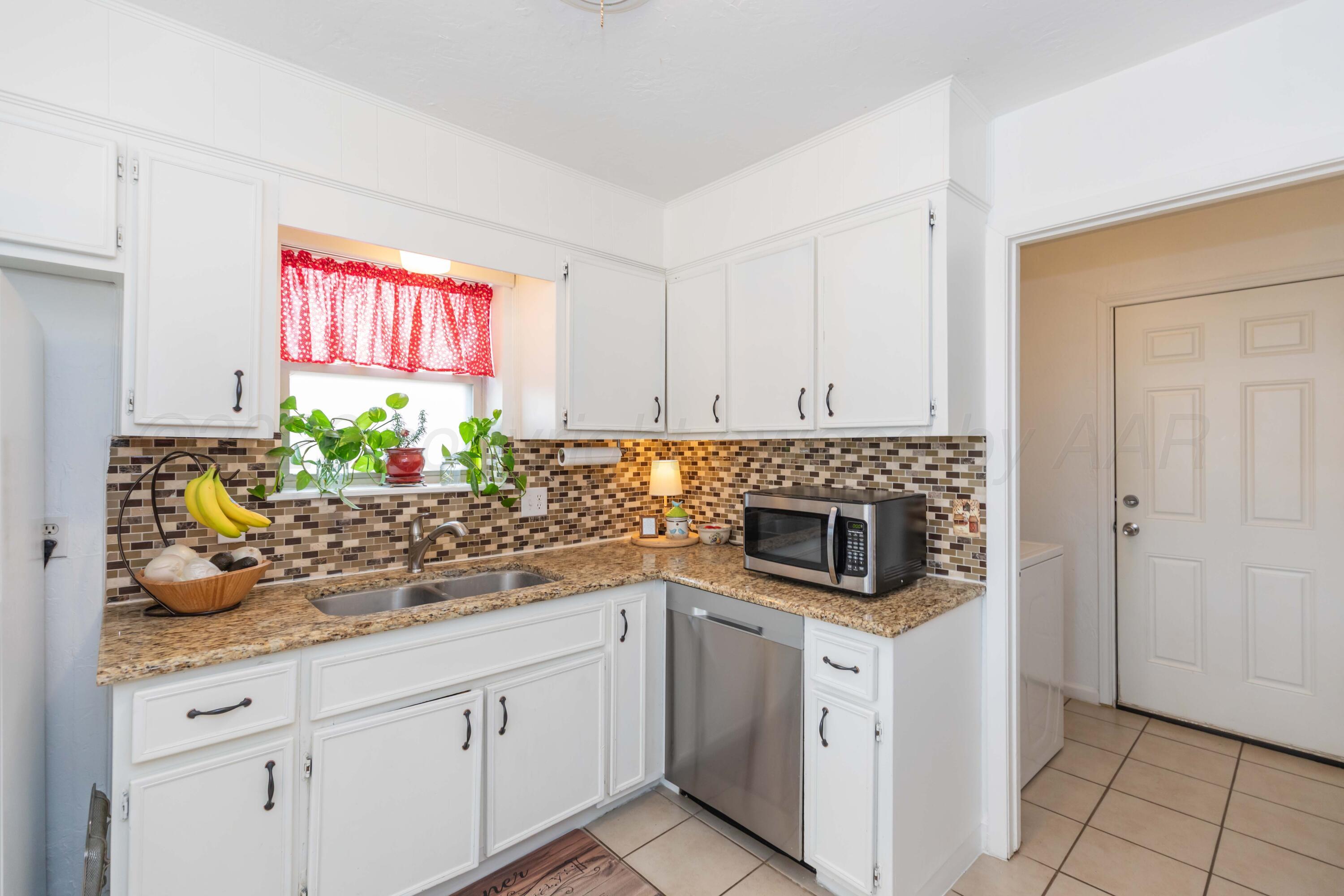 7308 Holyoke Trail Amarillo, TX 79121 - Photo 13 of 39 a kitchen with granite countertop a stove a sink and a microwave