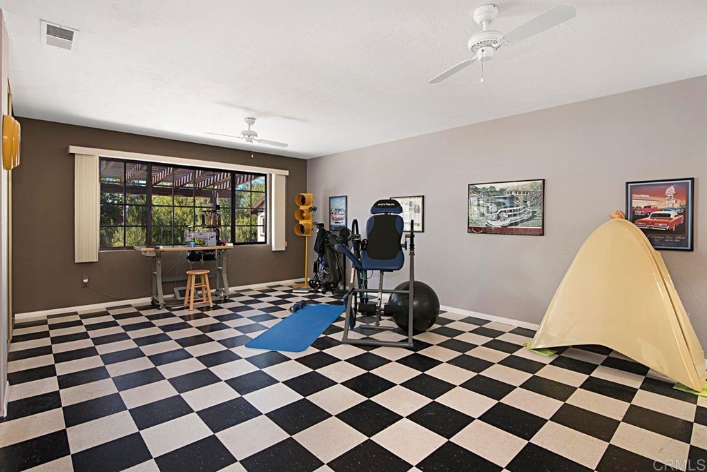 29573 Miller Road Valley Center, CA 92082 - Photo 22 of 37 a living room with a black white checkered floor with a gaming machine and dining chairs