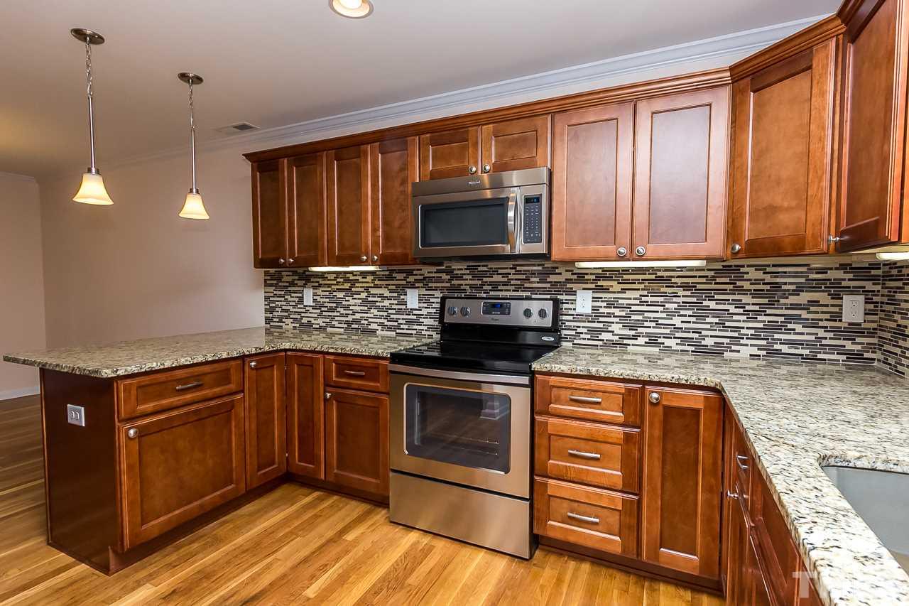 1237 Somerset Road Raleigh, NC 27610 - Photo 11 of 25 a kitchen with stainless steel appliances granite countertop wooden cabinets stove top oven and sink