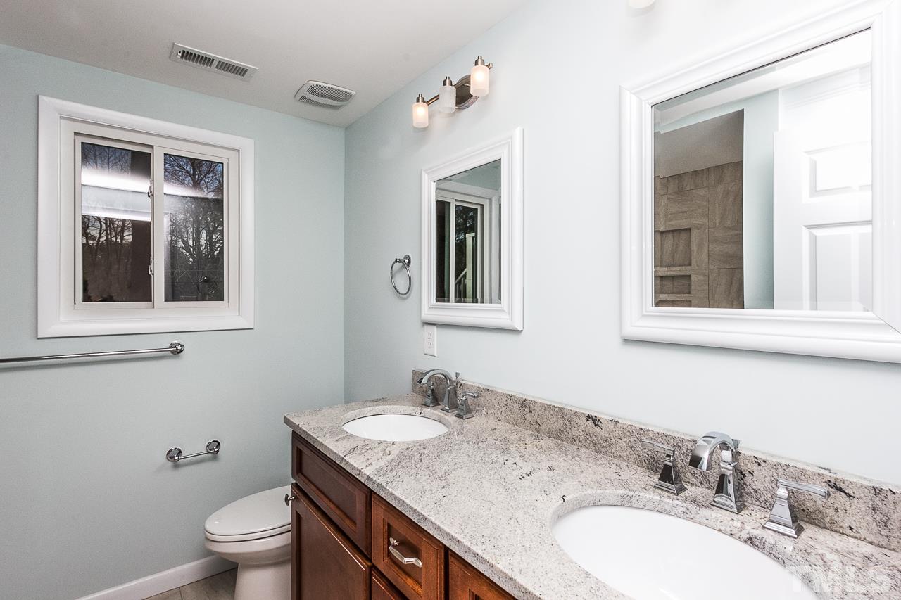 1237 Somerset Road Raleigh, NC 27610 - Photo 7 of 25 a bathroom with a granite countertop toilet a sink and a mirror