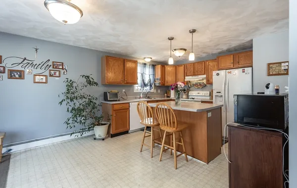 a kitchen with kitchen island a dining table chairs stainless steel appliances and cabinets