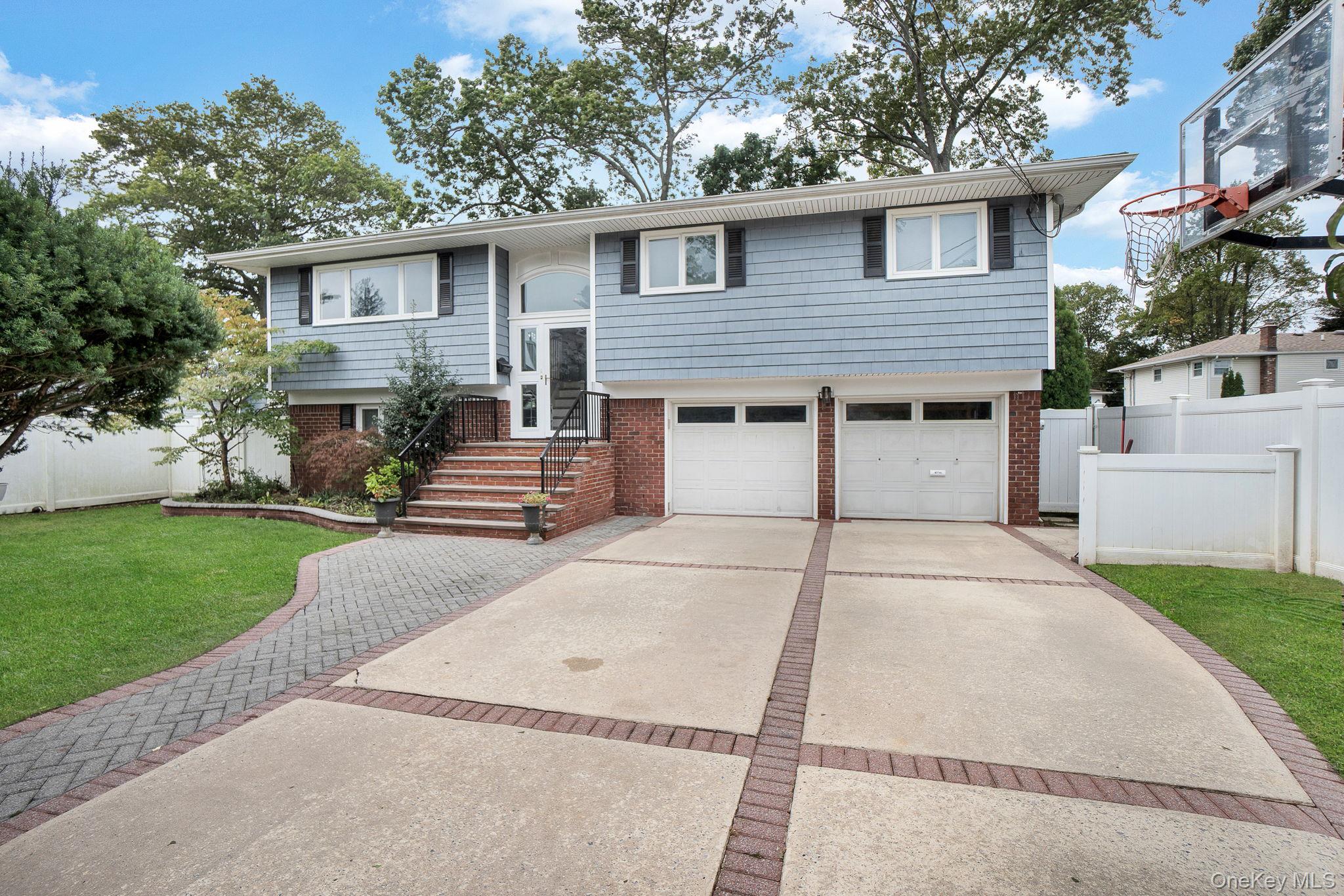Raised ranch with brick siding, driveway, and an attached garage