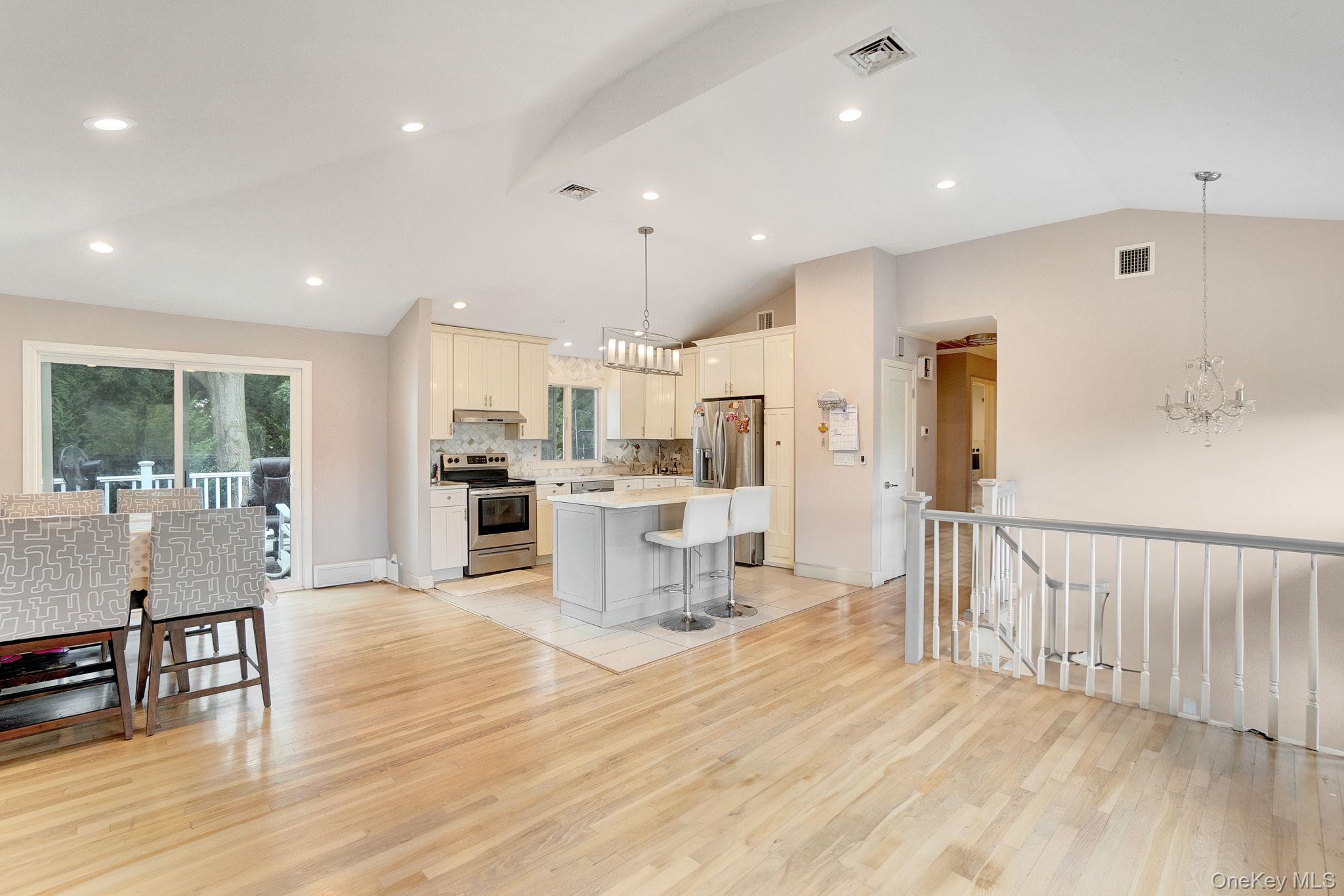 978 Little Whaleneck Road North Merrick, NY 11566 - Photo 16 of 32 Kitchen with a chandelier, a kitchen bar, lofted ceiling, decorative backsplash, and hanging light fixtures