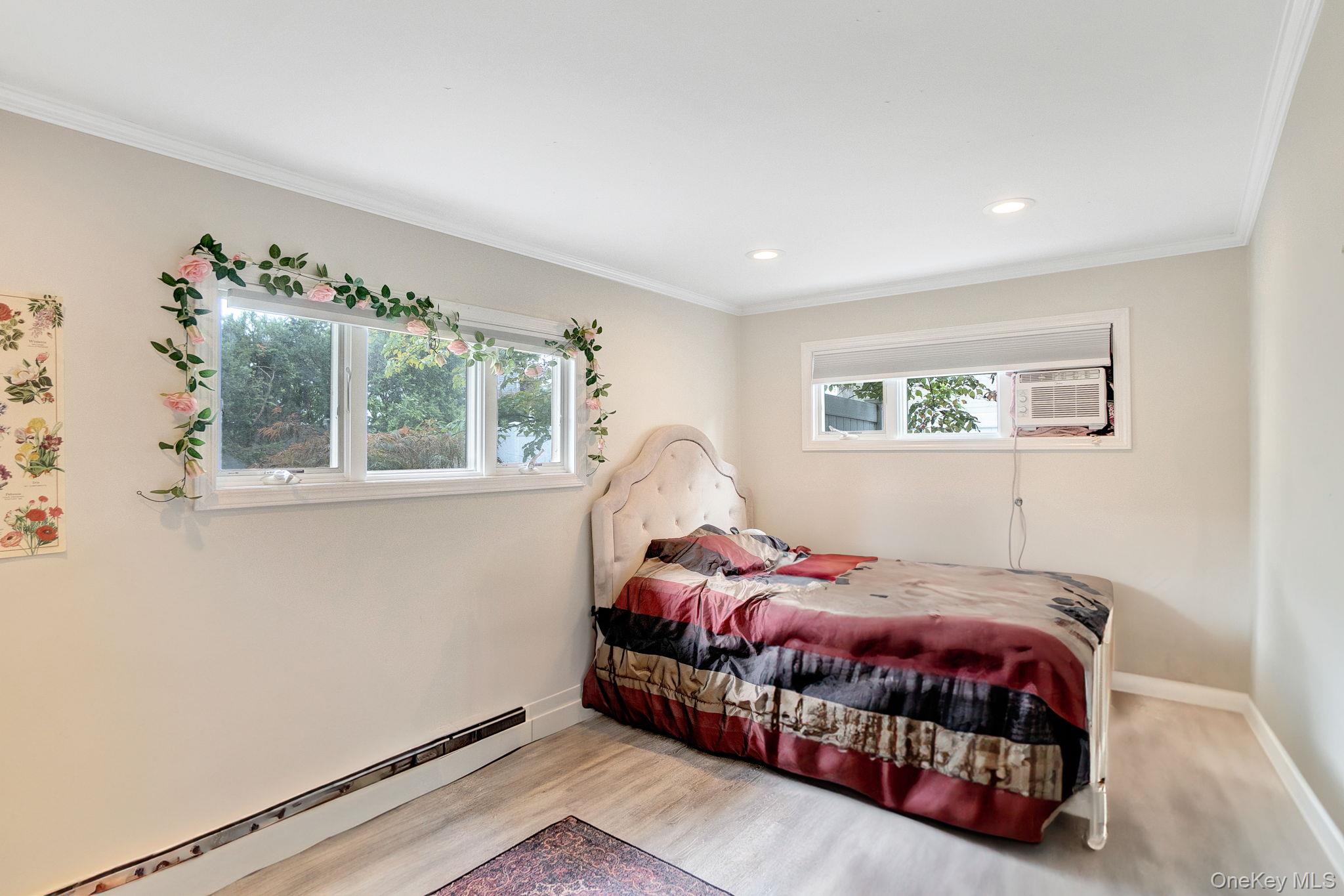 978 Little Whaleneck Road North Merrick, NY 11566 - Photo 18 of 32 Bedroom with baseboard heating, ornamental molding, wood finished floors, and recessed lighting