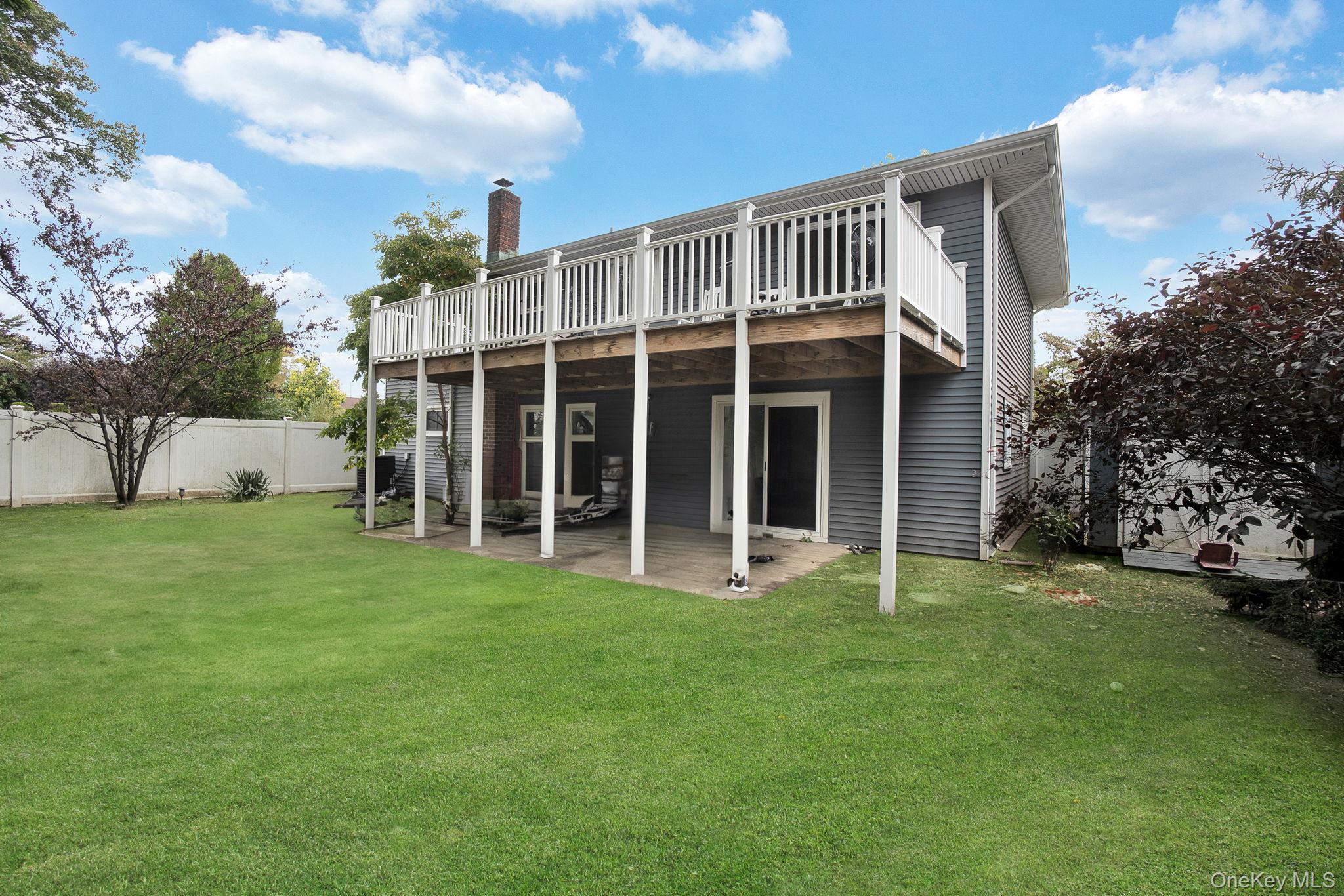 978 Little Whaleneck Road North Merrick, NY 11566 - Photo 29 of 32 Rear view of house with a deck, a chimney, and a patio