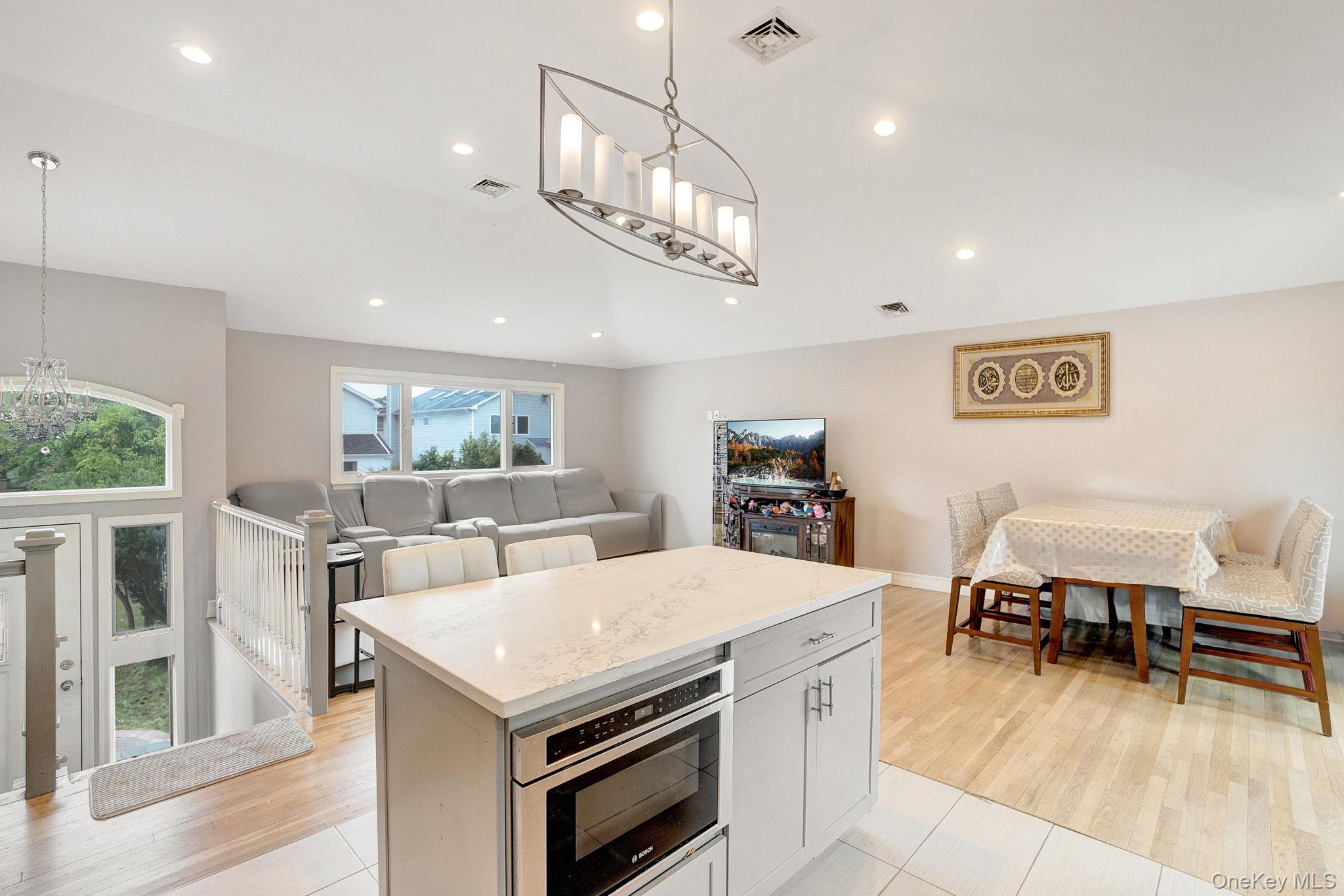 978 Little Whaleneck Road North Merrick, NY 11566 - Photo 32 of 32 Kitchen with a chandelier, open floor plan, light stone counters, recessed lighting, and a kitchen island