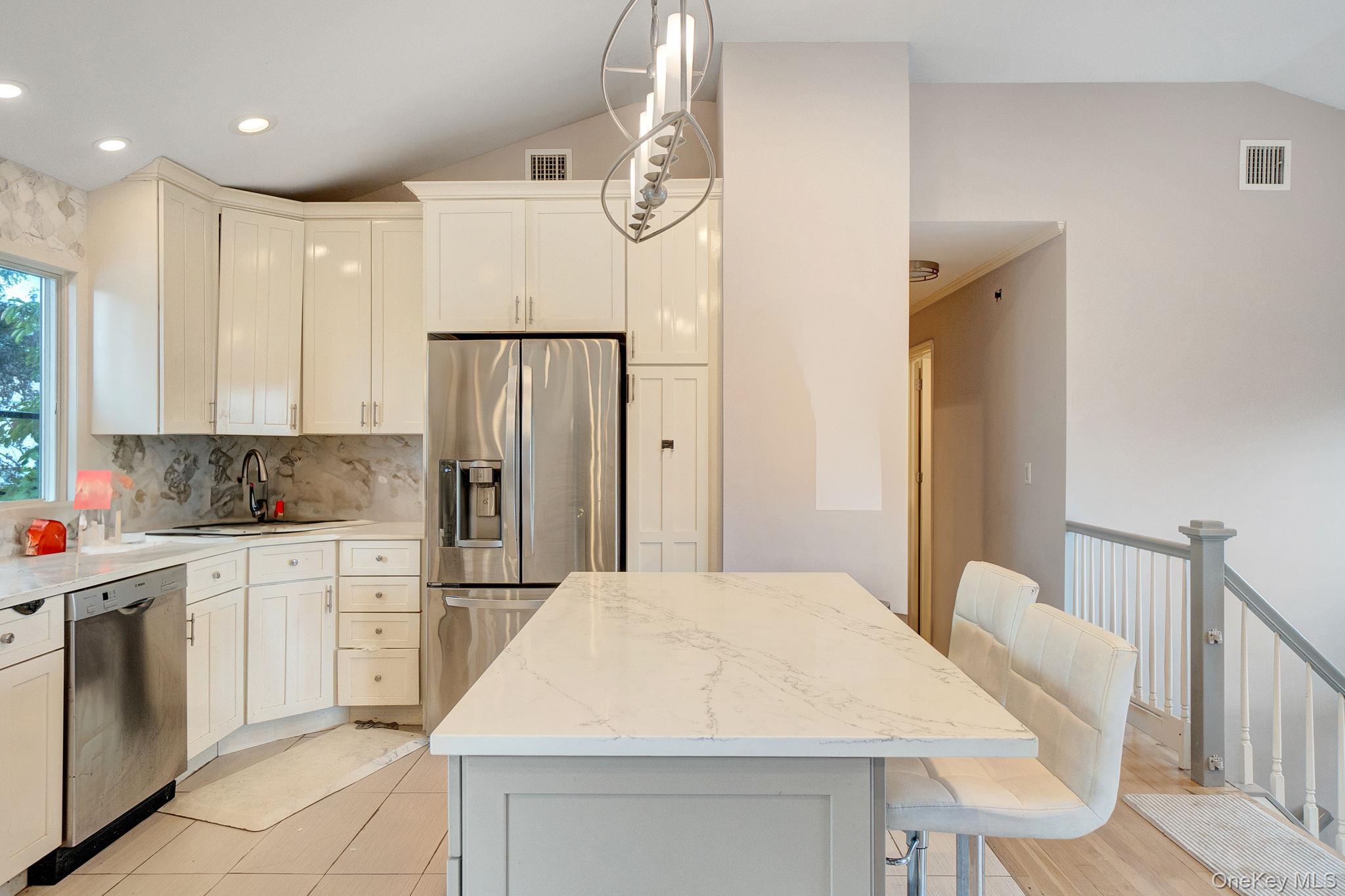 978 Little Whaleneck Road North Merrick, NY 11566 - Photo 5 of 32 Kitchen with lofted ceiling, appliances with stainless steel finishes, pendant lighting, a kitchen breakfast bar, and backsplash