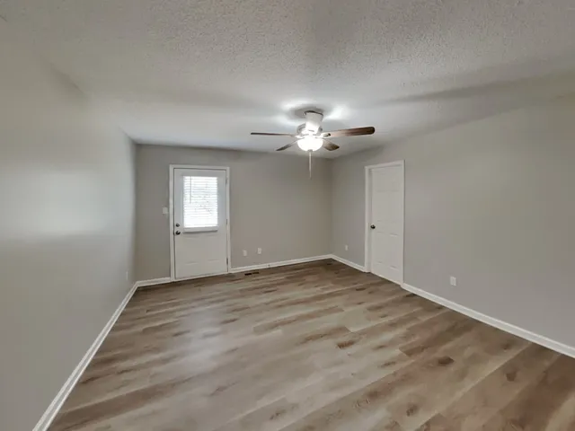 a view of a room with wooden floor and a ceiling fan