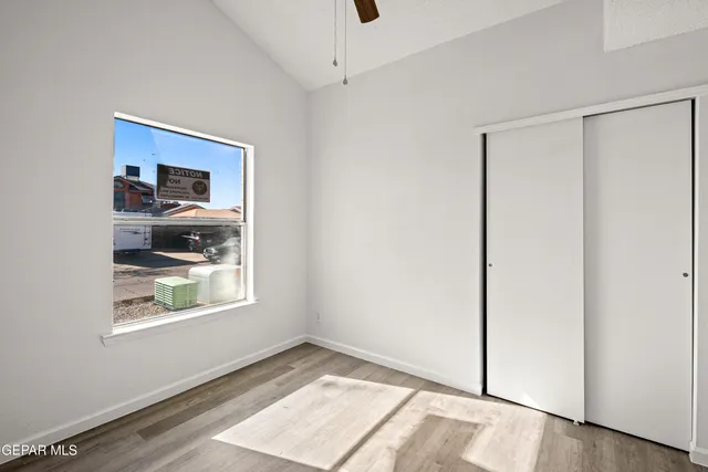 a view of an empty room with window and wooden floor