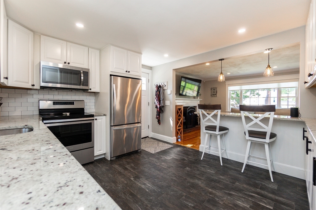 23 Thistledale Road Wakefield, MA 01880 - Photo 12 of 41 a kitchen with stainless steel appliances kitchen island granite countertop a refrigerator oven a sink dishwasher and white cabinets with wooden floor