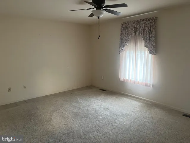 an empty room with a window and a fan