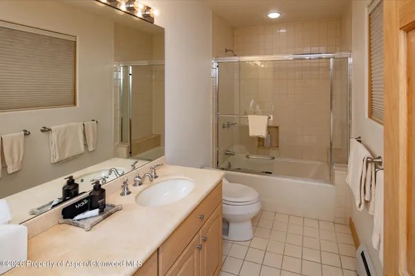 a bathroom with a bathtub shower sink mirror and toilet