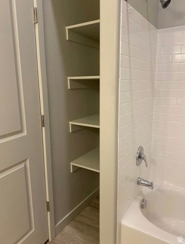 618 South 100 West, Unit 303 Springville, UT 84663 - Photo 9 of 11 Built-in shelving, white subway tile shower surround, white bathtub, chrome shower fixture, wood-finish flooring