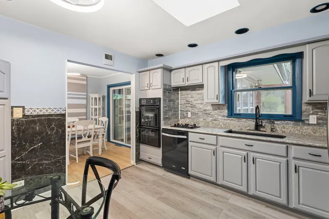 a kitchen with stainless steel appliances granite countertop a stove a sink dishwasher a refrigerator and white cabinets with wooden floor