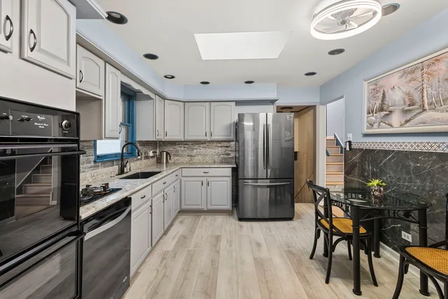 a kitchen with a refrigerator a stove and a dining table with wooden floor