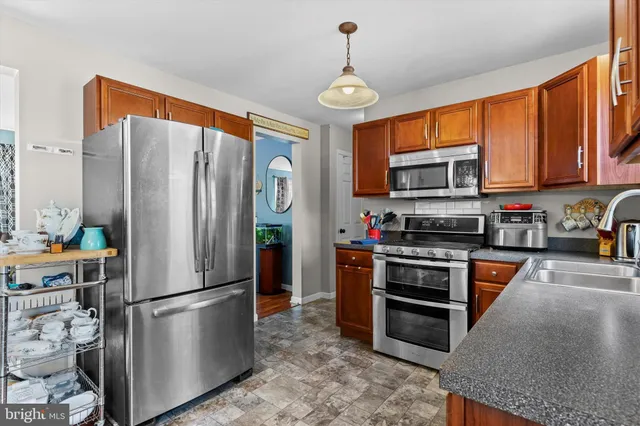 a kitchen with stainless steel appliances granite countertop a refrigerator a stove top oven a sink dishwasher and wooden cabinets