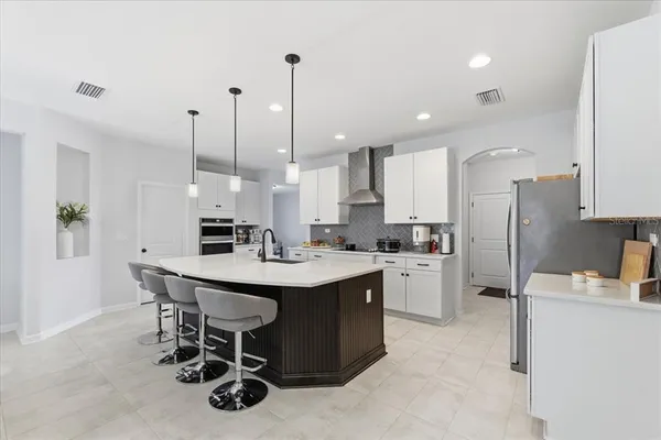 a kitchen with a sink a center island stainless steel appliances and cabinets