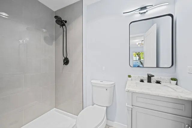 a bathroom with a toilet a sink a mirror a vanity and shower