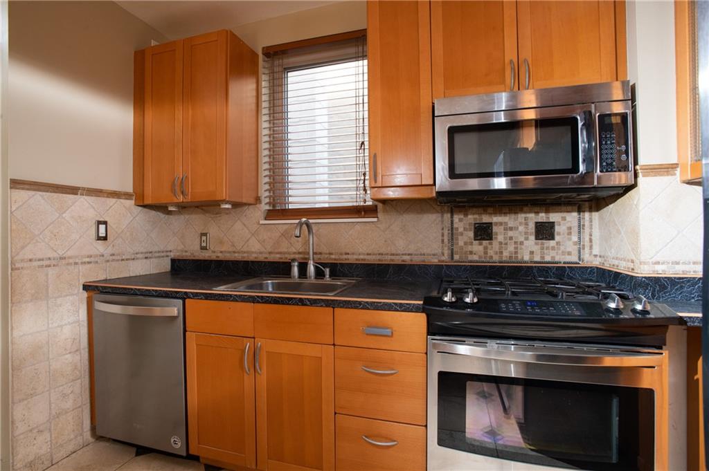 15 Frazier Avenue McKees Rocks, PA 15136 - Photo 5 of 11 a kitchen with stainless steel appliances a stove a microwave a sink and cabinets