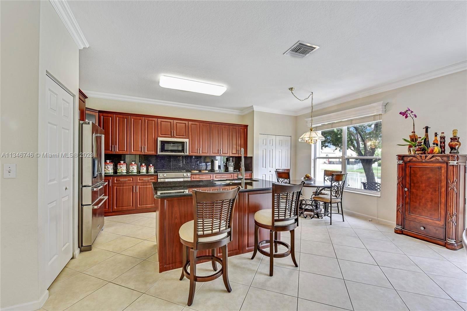 16392 Southwest 29th Street Miramar, FL 33027 - Photo 21 of 30 a kitchen with stainless steel appliances a dining table chairs and window