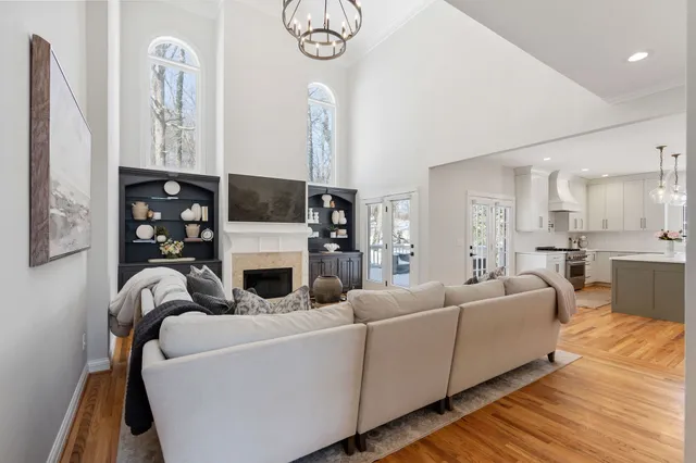 a living room with furniture a fireplace and white kitchen view