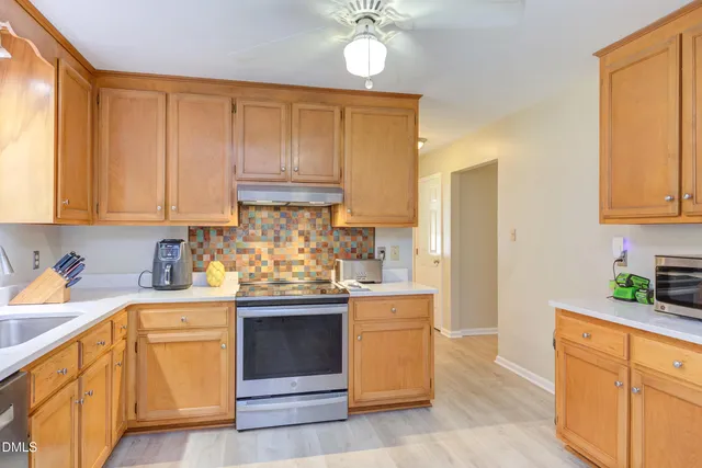 a kitchen with stainless steel appliances a dining table chairs refrigerator and sink