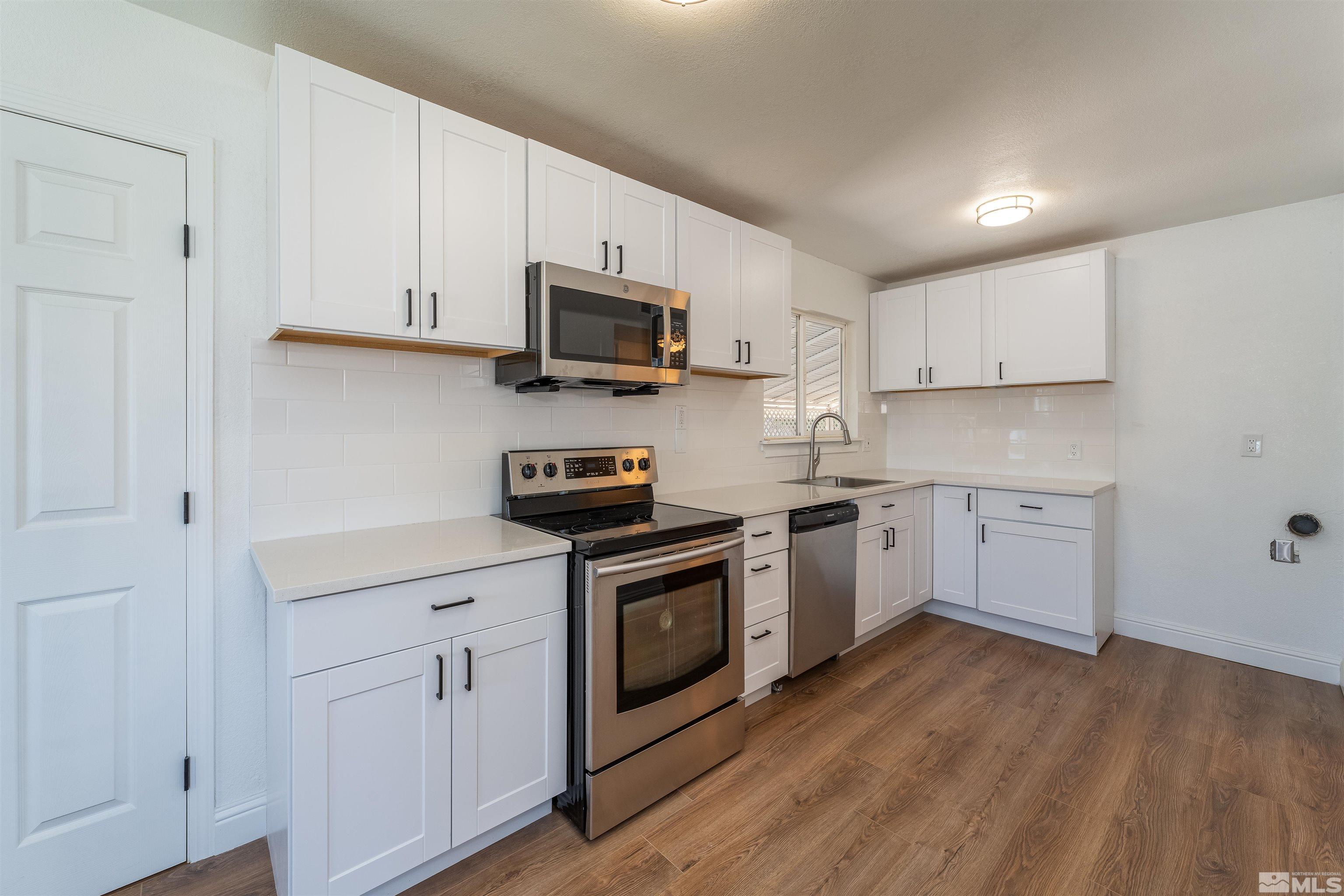 1815 Radcliffe Drive Reno, NV 89502 - Photo 8 of 22 a kitchen with stainless steel appliances granite countertop white cabinets a sink a stove a microwave and cabinetry