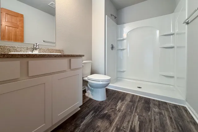 a bathroom with a granite countertop toilet a mirror and a shower