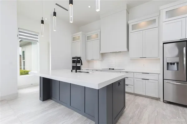 a kitchen with a sink a stove a refrigerator and white cabinets