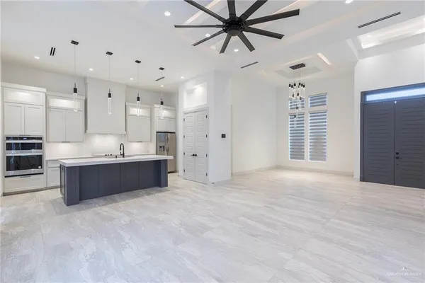 a large white kitchen with kitchen island a sink stainless steel appliances and a counter top space