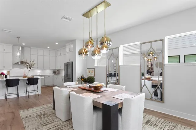 a dining room with furniture a kitchen a chandelier and wooden floor